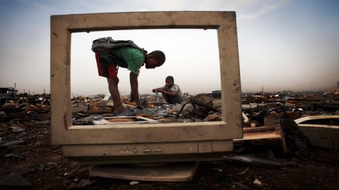 Unos niños recogen la parte metálica de una pantalla, en Agbogbloshie, barrio de Accra, Ghana. No se protegen para manipular productos químicos como el mercurio o el plomo.