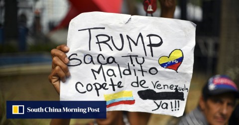 A woman holds up a sign against US President Donald Trump’s intervention in Venezuela, during a signature campaign to urge the United States’ to put a halt to intervention threats against Venezuelan President Nicolas Maduro’s government, at Bolivar square in Caracas.