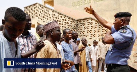 在尼日利亞總統選舉期間，在阿達瑪瓦州約拉的首都學校投票部門，一名保安人員示意投票。