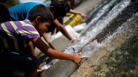 人們在2019年3月11日在委內瑞拉的加拉加斯收集通過污水排放物釋放的水，該污水排放物進入該城市大部分廢水的瓜伊爾河。