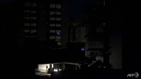 在加拉加斯停電期間，人們坐在他們家外面的燈上。