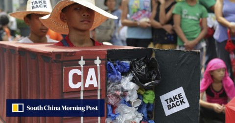Environmental activists wear a mock container filled with garbage. 