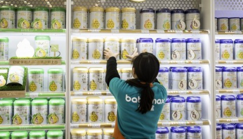 An employee arranges cans of Illuma infant formula, produced by Nestlé, on a shelf at store in Shanghai. Photo: Bloomberg