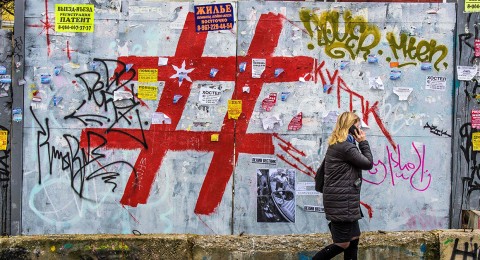 A woman speaks on a phone as she walks past a graffiti-covered wall with a giant hashtag sign near Moscow's Kursky railway station on Nov. 17, 2017. | Mladen Antonov/Getty Images