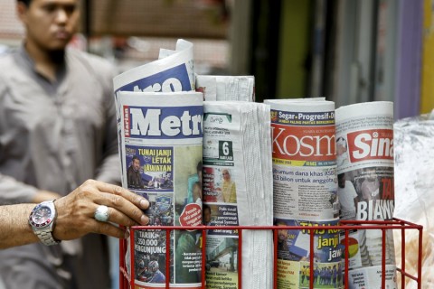 A man takes a copy of a newspaper at a grocery shop in Shah Alam, Malaysia, on March 26, 2018. Photo: Sadiq Asyraf / AP