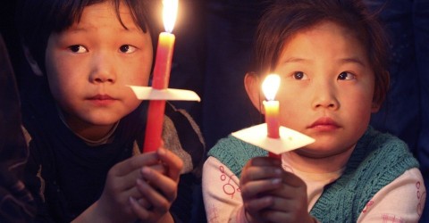 Children hold candles during the Easter mass at a church in Xiaohan village of Tianjin municipality in 2009. Photo: Vincent Du / Reuters