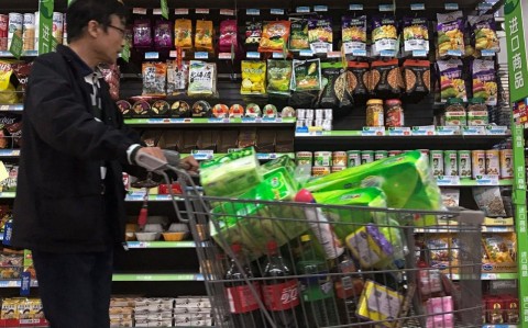 A man pushes a shopping cart past a display of nuts imported from the US and other countries in a Beijing supermarket. Photo: AP