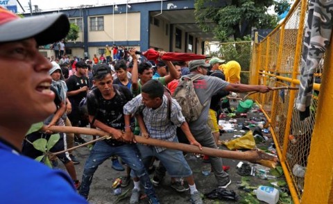 Cientos de migrantes centroamericanos que hacen parte de una segunda caravana rumbo a los Estados Unidos se enfrentan a la policía en el paso fronterizo entre México y Guatemala